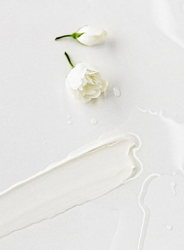 Close-up of gentle cleansing milk texture with a flower on a white background.