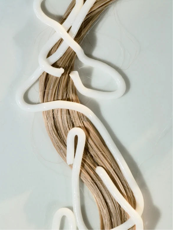 Hair extensions with white clips on a light gray background