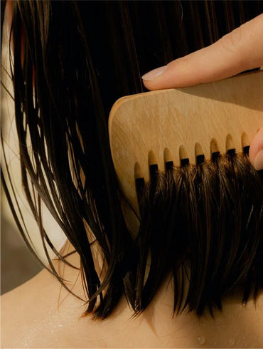 Person combing their hair with a wooden comb