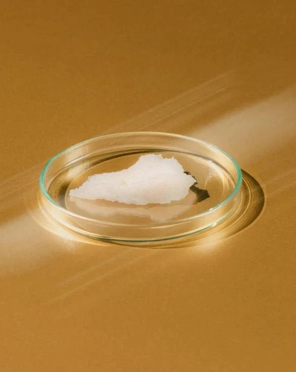 Close-up of gentle cleansing milk texture in a glass on an orange background.