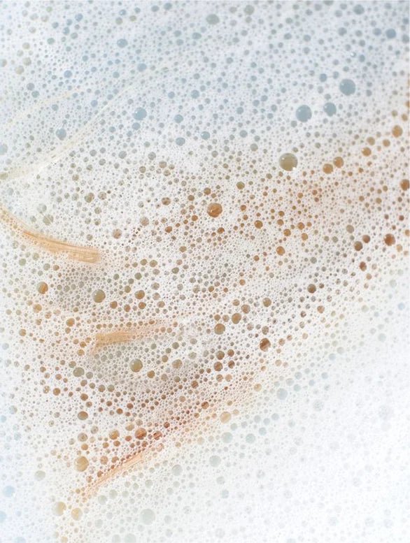 Close-up of a soapy water surface with bubbles and soap scum.