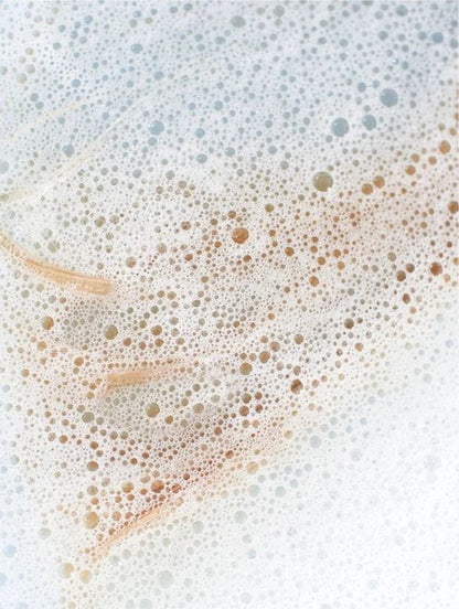 Close-up of a soapy water surface with bubbles and soap scum.