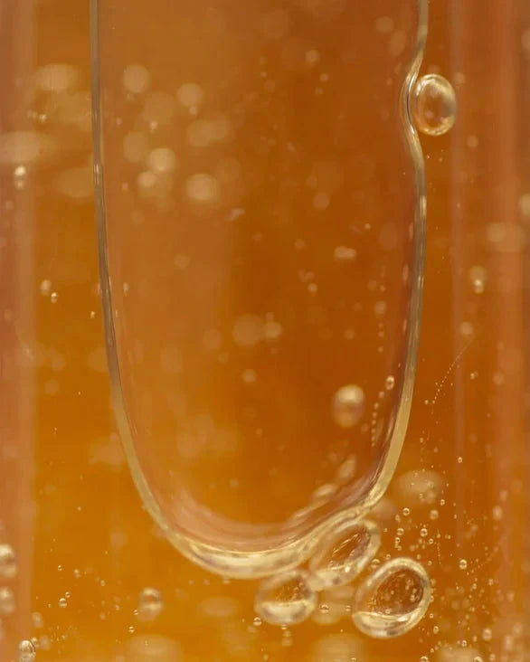 Close-up of a droplet of orange liquid with bubbles on a blurred orange background