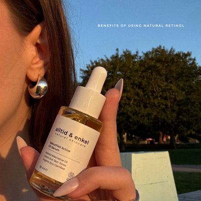 Person holding a bottle of 'alltid & enkel' natural skincare product with a scenic background.