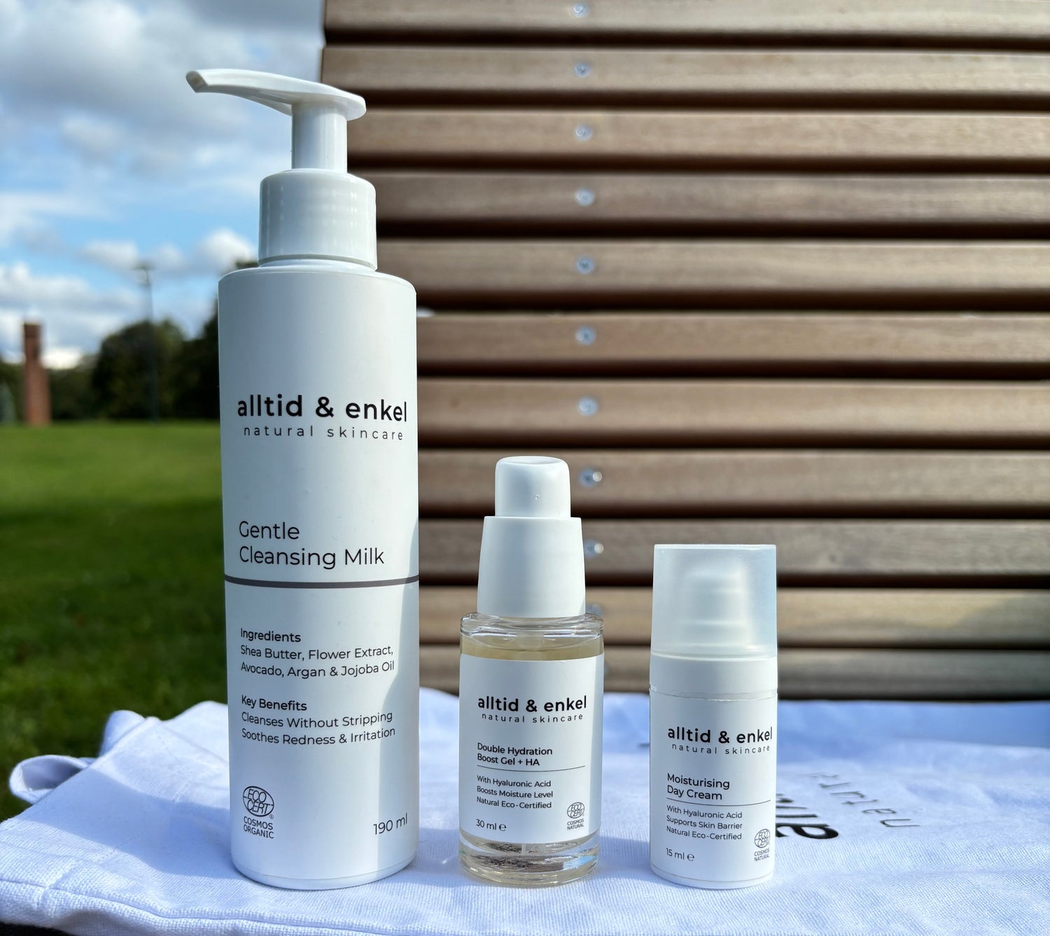 Three skincare products on a white towel with a wooden background