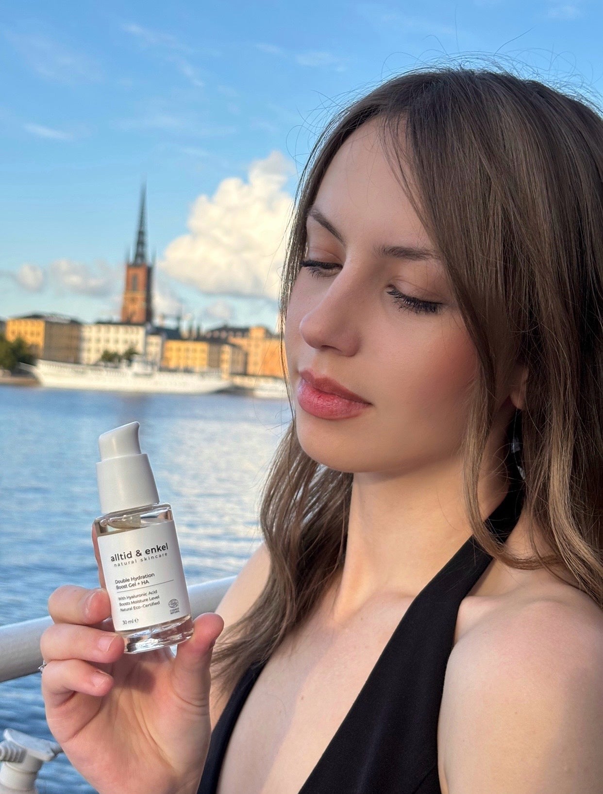 Woman holding a skincare product with a scenic background
