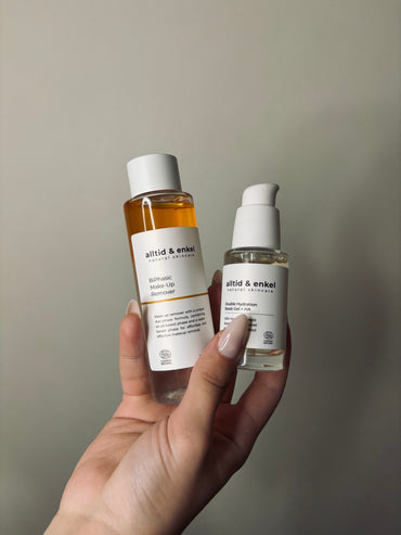 Hand holding two skincare bottles labeled 'alltid & enkel' against a neutral background.