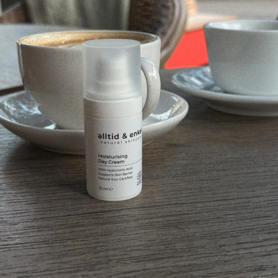 Moisturizing day cream on a table with a cup of coffee in the background.