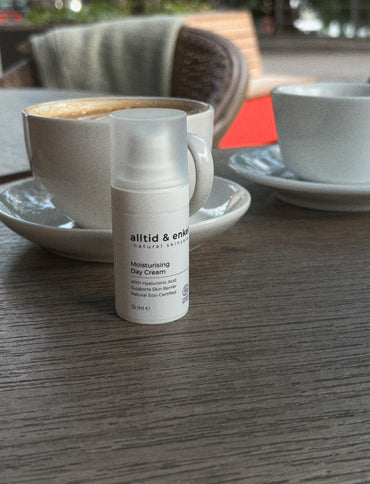 Moisturizing day cream on a table with a cup of coffee in the background.