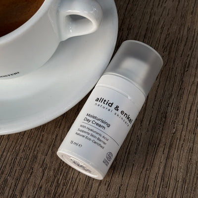 Natural moisturising cream bottle next to a cup of coffee on a wooden surface.