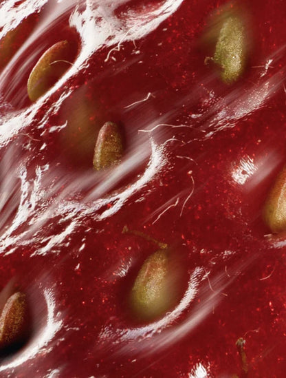 Close-up of a strawberry with seeds on a red background