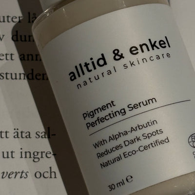 Natural pigment perfecting serum bottle, on a printed paper background.