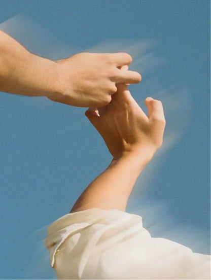 Two hands reaching towards each other against a blue sky