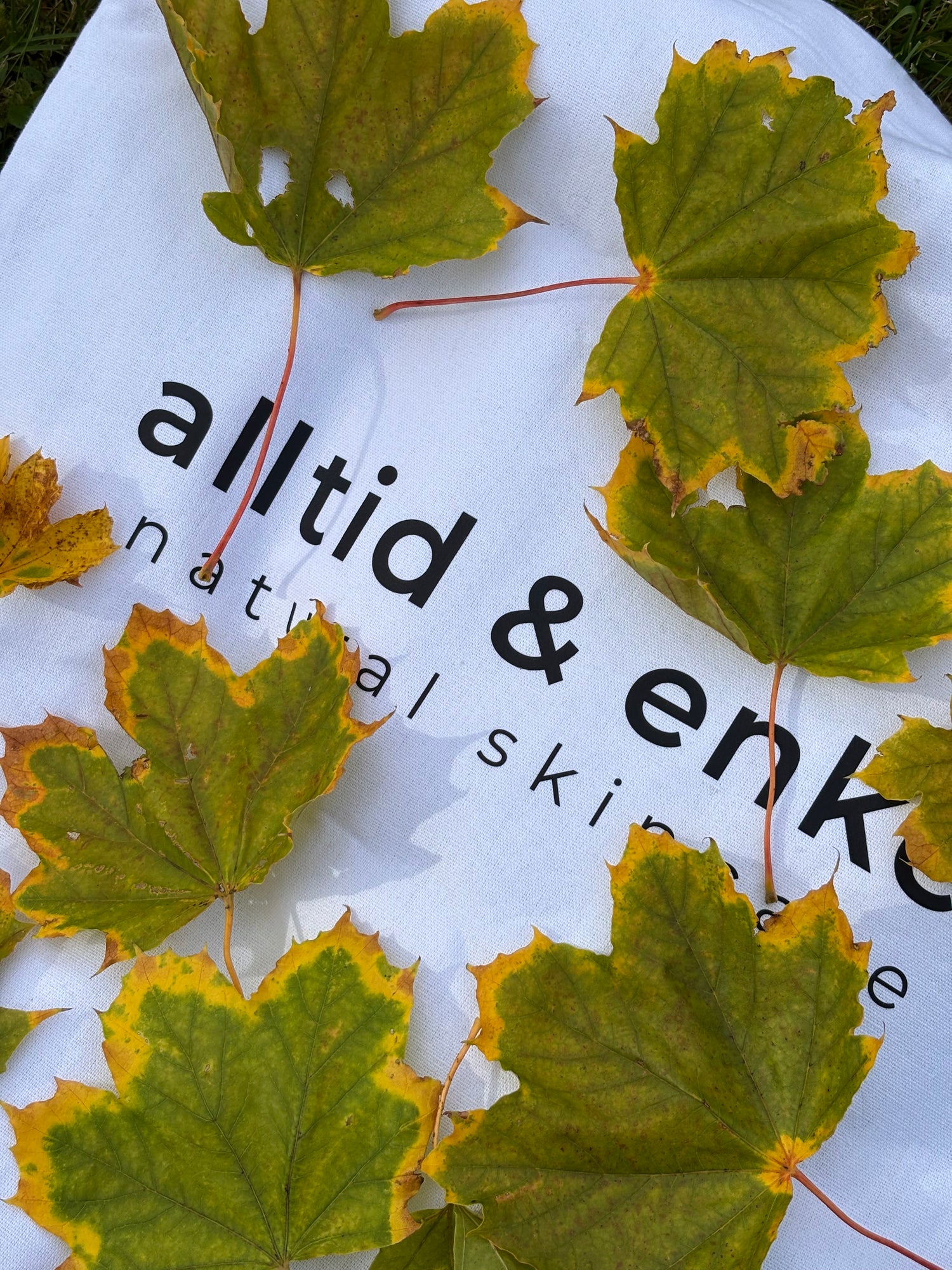 Green leaves on a white shopper bag with  logo.