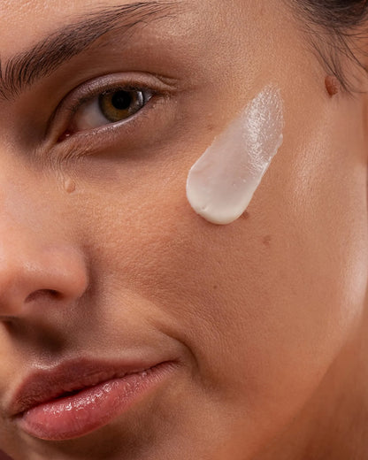 Close-up of a woman's face with a skincare product applied to her cheek.