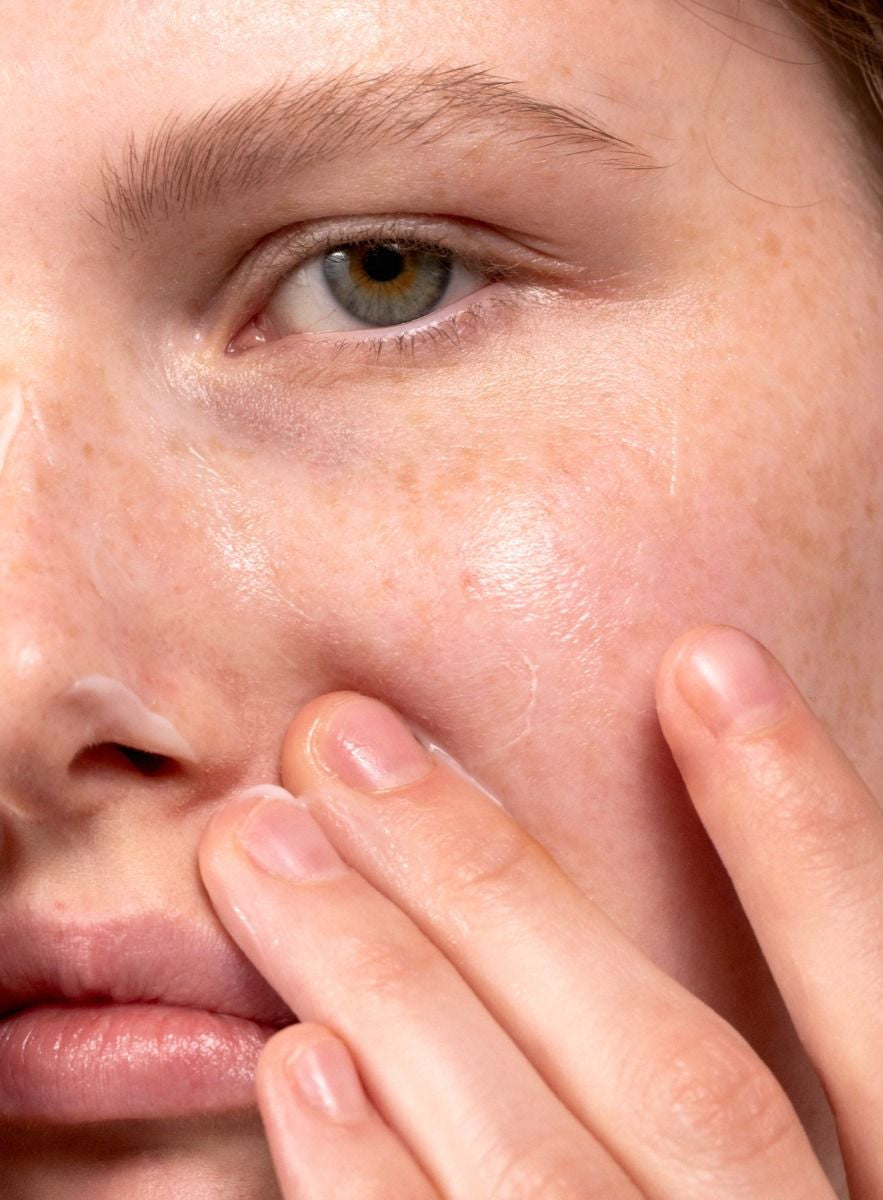 Close-up of a person's eye and cheek with a finger touching the skin.