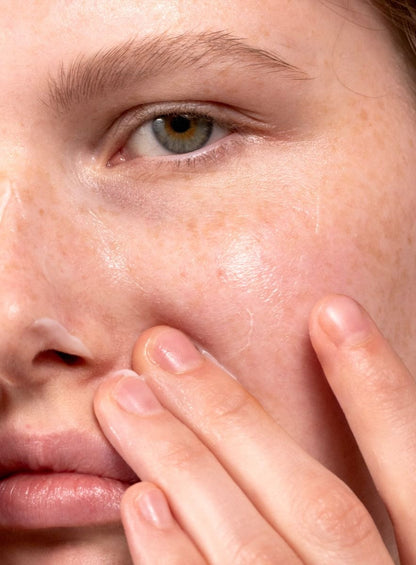Close-up of a person's eye and cheek with a finger touching the skin.