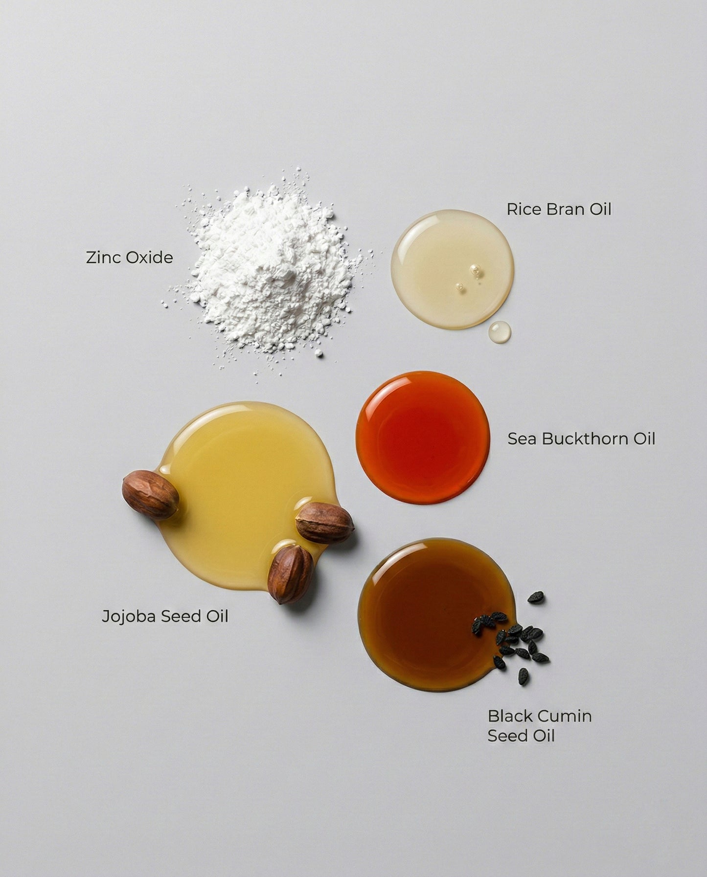 Various natural ingredients including zinc oxide, rice bran oil, jojoba seed oil, sea buckthorn oil, and black cumin seed oil on a gray background.
