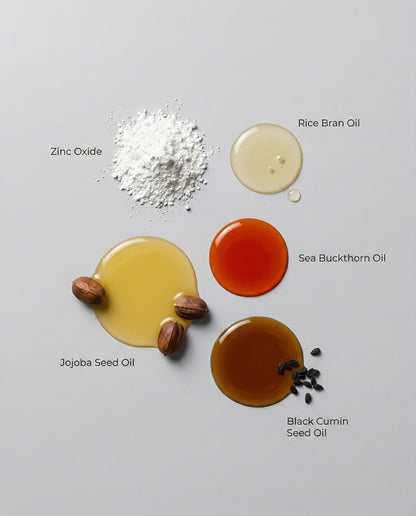 Various natural ingredients including zinc oxide, rice bran oil, jojoba seed oil, sea buckthorn oil, and black cumin seed oil on a gray background.