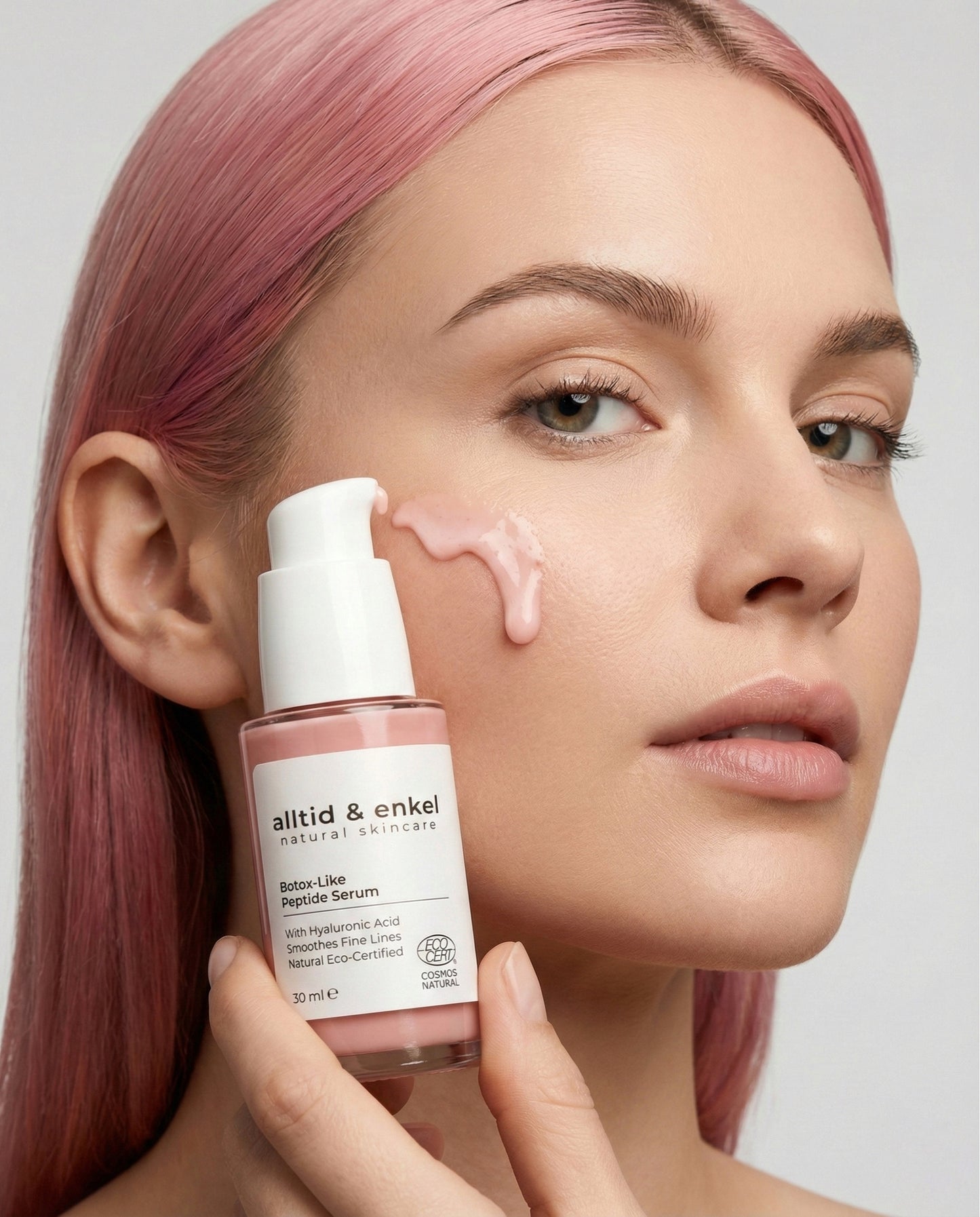 Woman applying a skincare serum to her face with a bottle labeled 'alltid & enkel' visible.