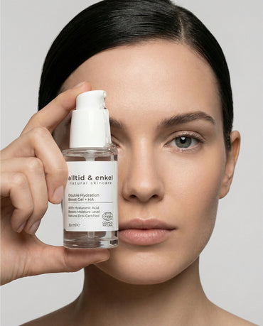 Woman holding a bottle of 'alltid & enkel' skincare product against a neutral background
