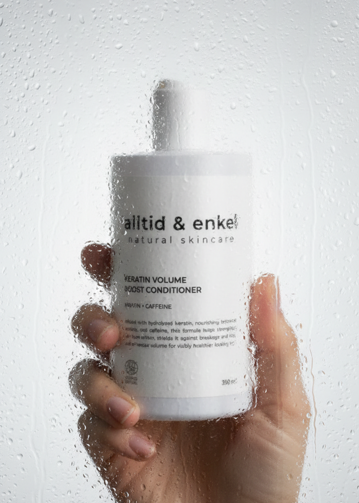 Hand holding a bottle of 'alltid & enkel' conditioner against a light background