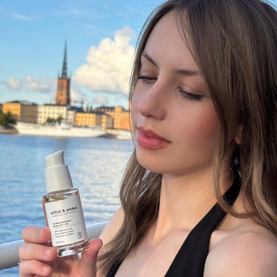 Woman holding a Double Hydration Boost Gel + HA bottle with a scenic background