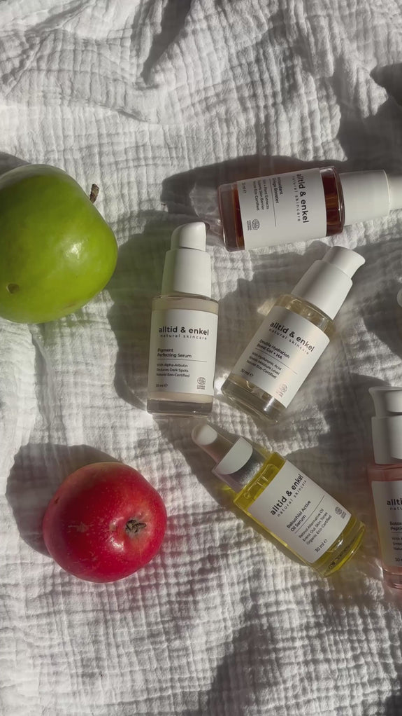 Assortment of skincare serums arranged on a light background next to fresh apples, highlighting natural ingredients and beauty products.
